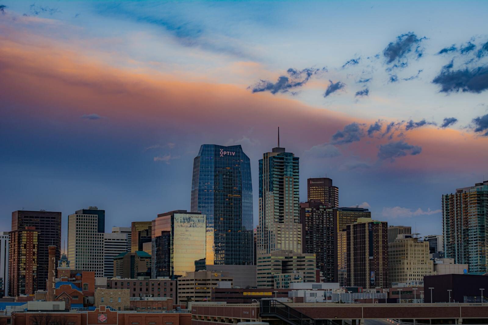 Denver Colorado cityscape with skyscrapers under a colorful sunset sky