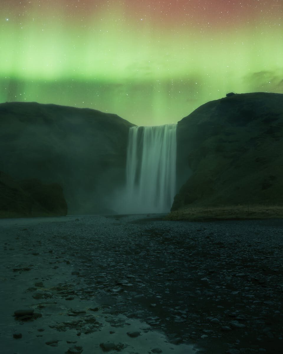 Northern Lights aurora borealis in vivid green and purple over an Icelandic landscape at night — a free natural wonder