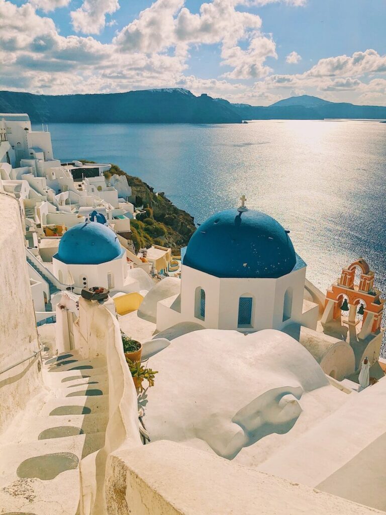 Santorini Greece travel guide - white-washed buildings and blue domes of Oia overlooking the Aegean Sea