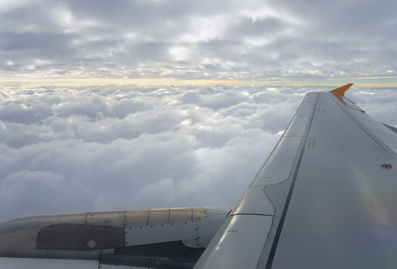 View over an airplane wing soaring between clouds on an international flight