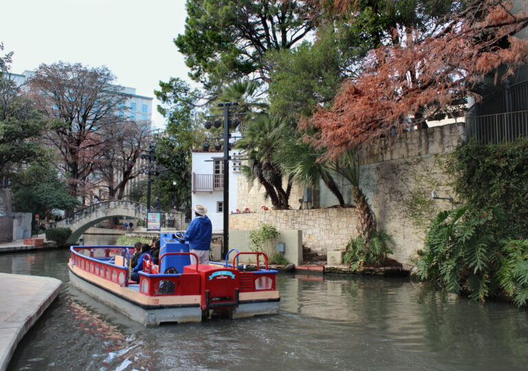 The San Antonio River Walk lined with cypress trees, restaurants, and stone footpaths below downtown