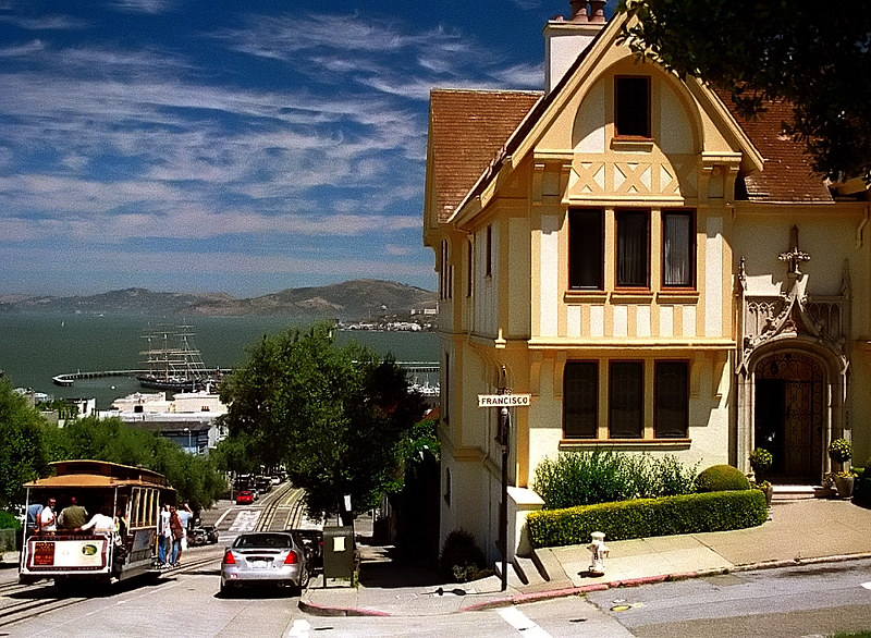 Historic cable car on Hyde Street with Victorian houses in San Francisco