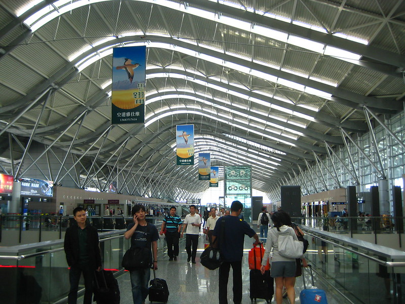 Travelers walking through a bright, modern airport terminal