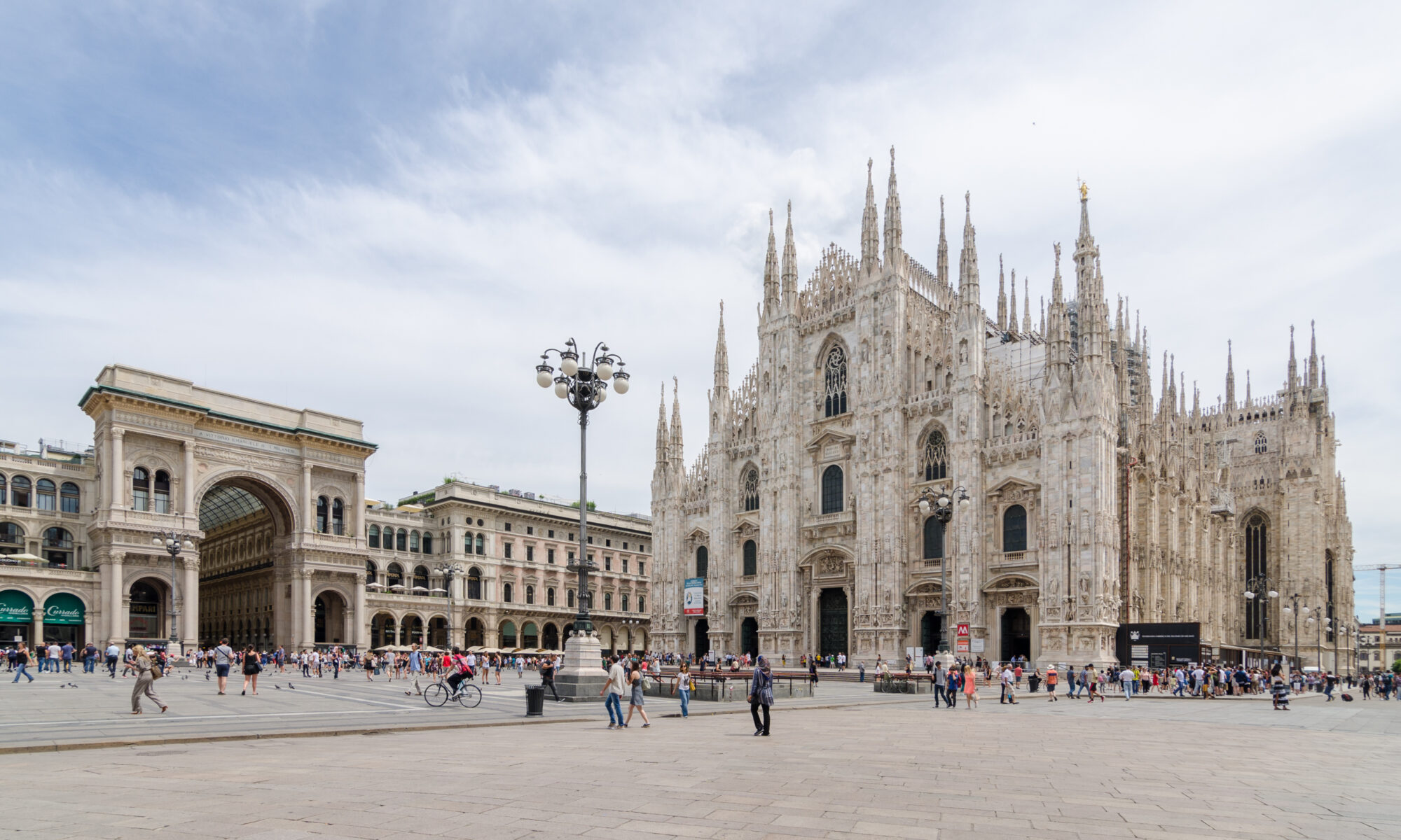 The white marble Gothic facade of the Duomo di Milano against a blue sky