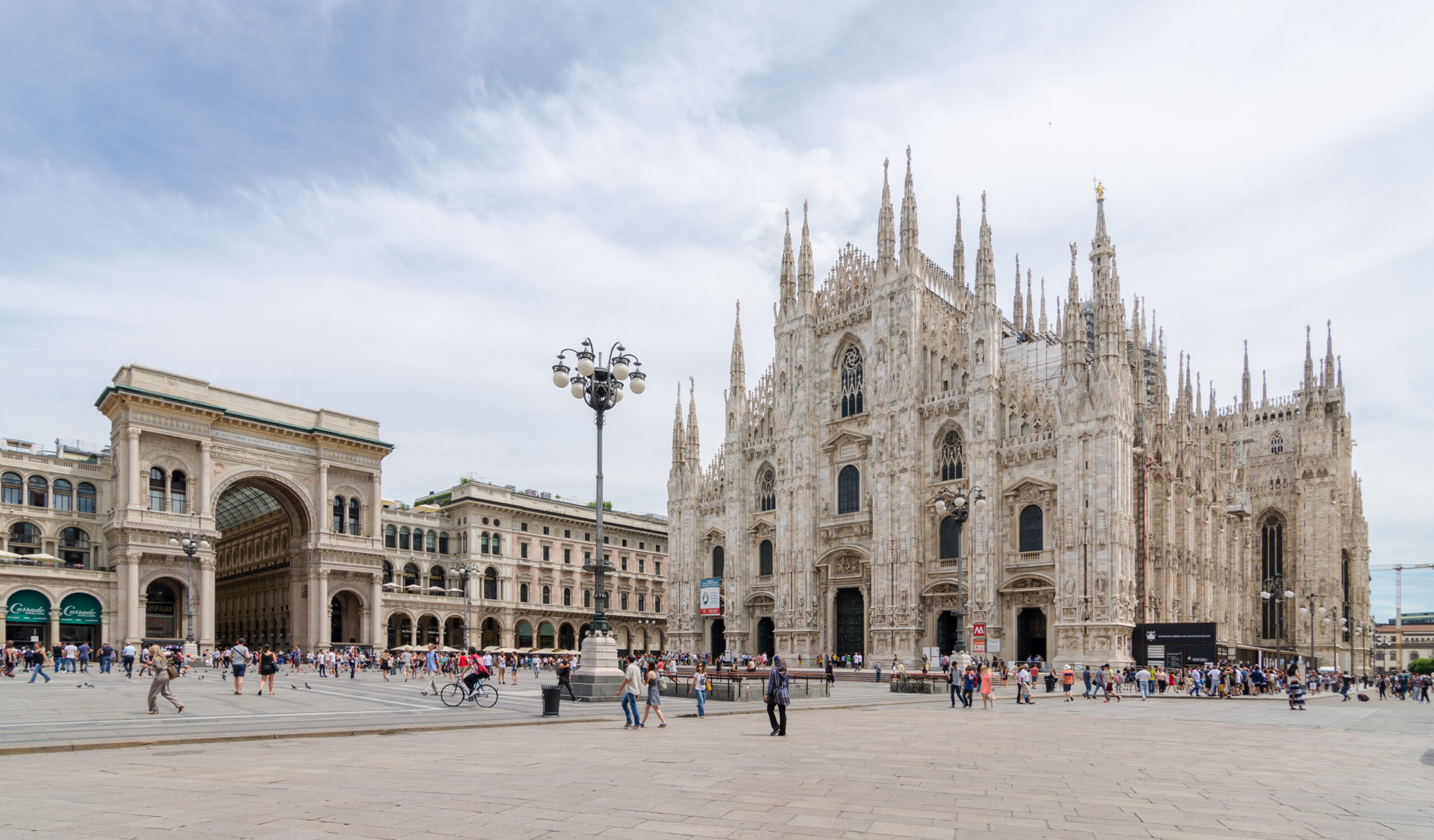 The white marble Gothic facade of the Duomo di Milano against a blue sky