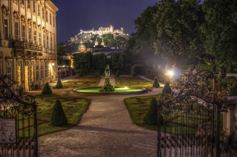 Mirabell Gardens with Hohensalzburg Fortress lit up behind in Salzburg, Austria