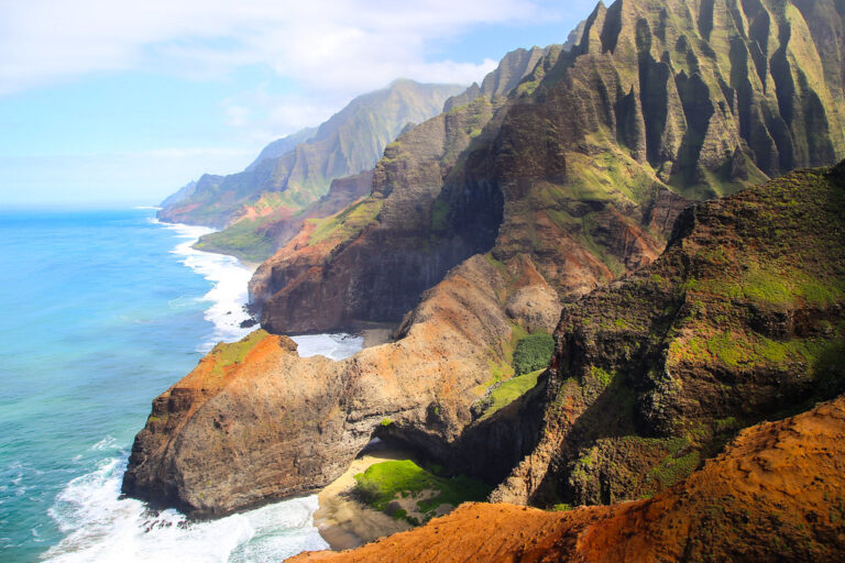 Emerald Na Pali Coast cliffs meeting turquoise ocean on Kauai, Hawaii