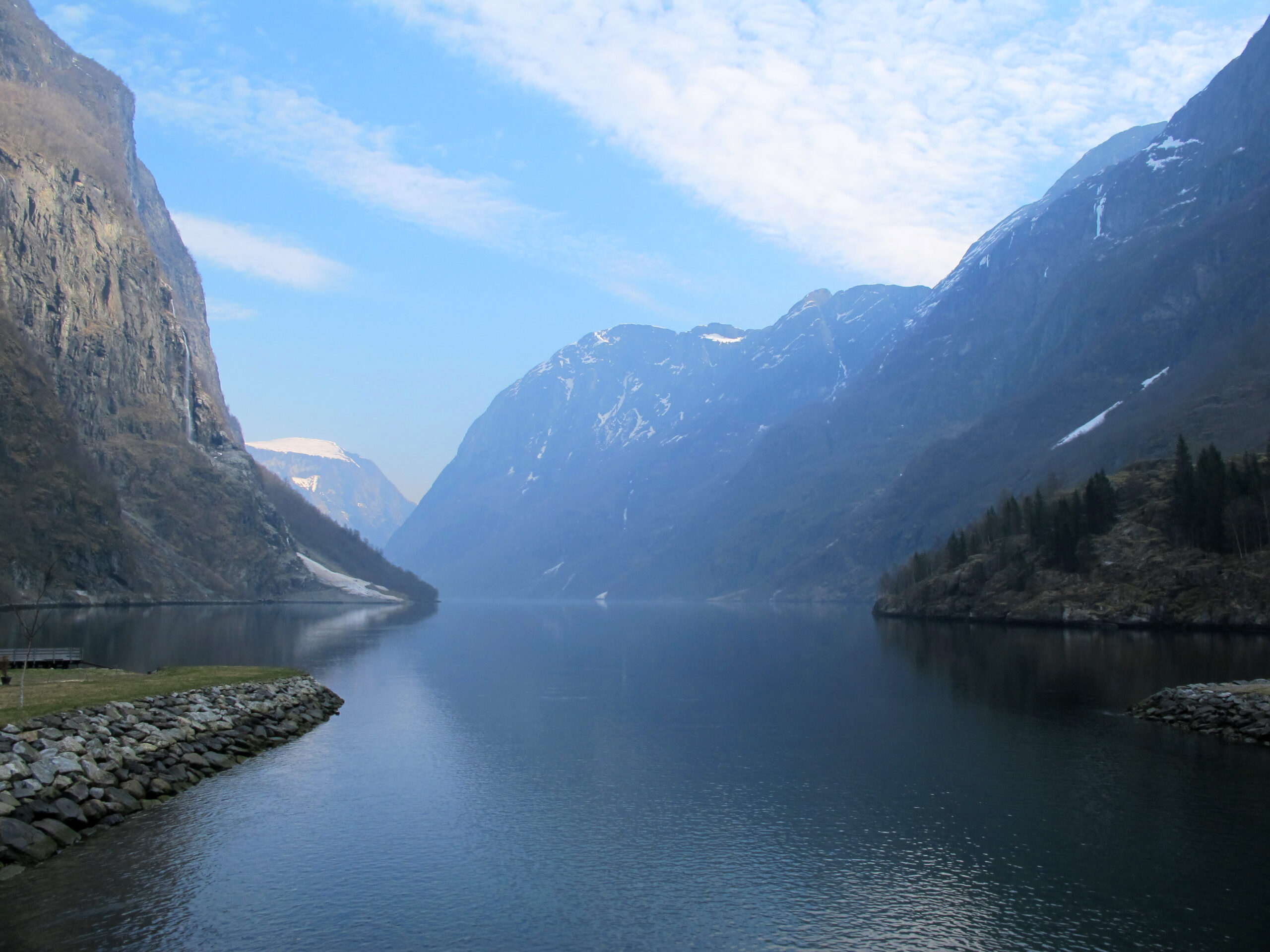 Steep green cliffs plunging into the calm Naeroyfjord, a UNESCO fjord near Bergen