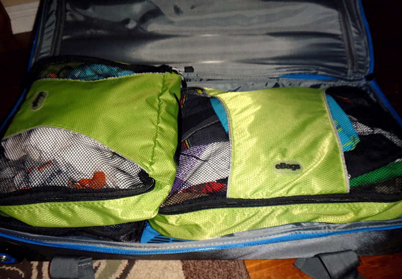 Open suitcase neatly packed with clothes and colorful packing cubes
