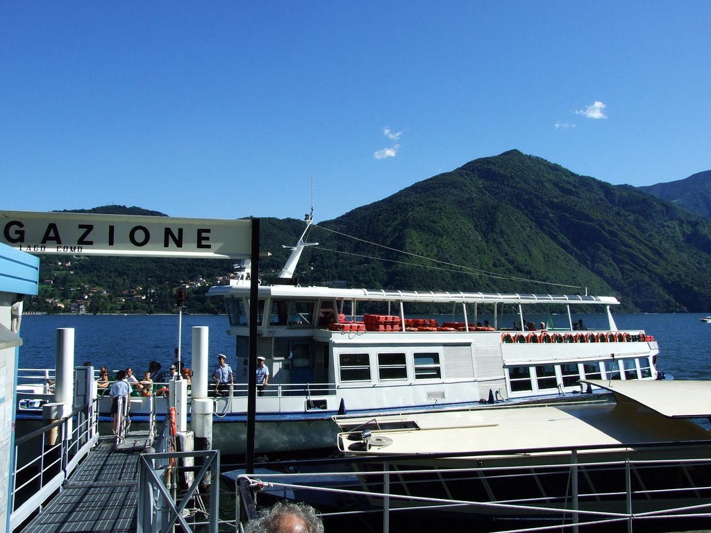 Passenger ferry at a Lake Como dock with mountains rising behind