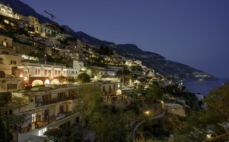 Positano colorful houses lit up at dusk cascading down the cliff