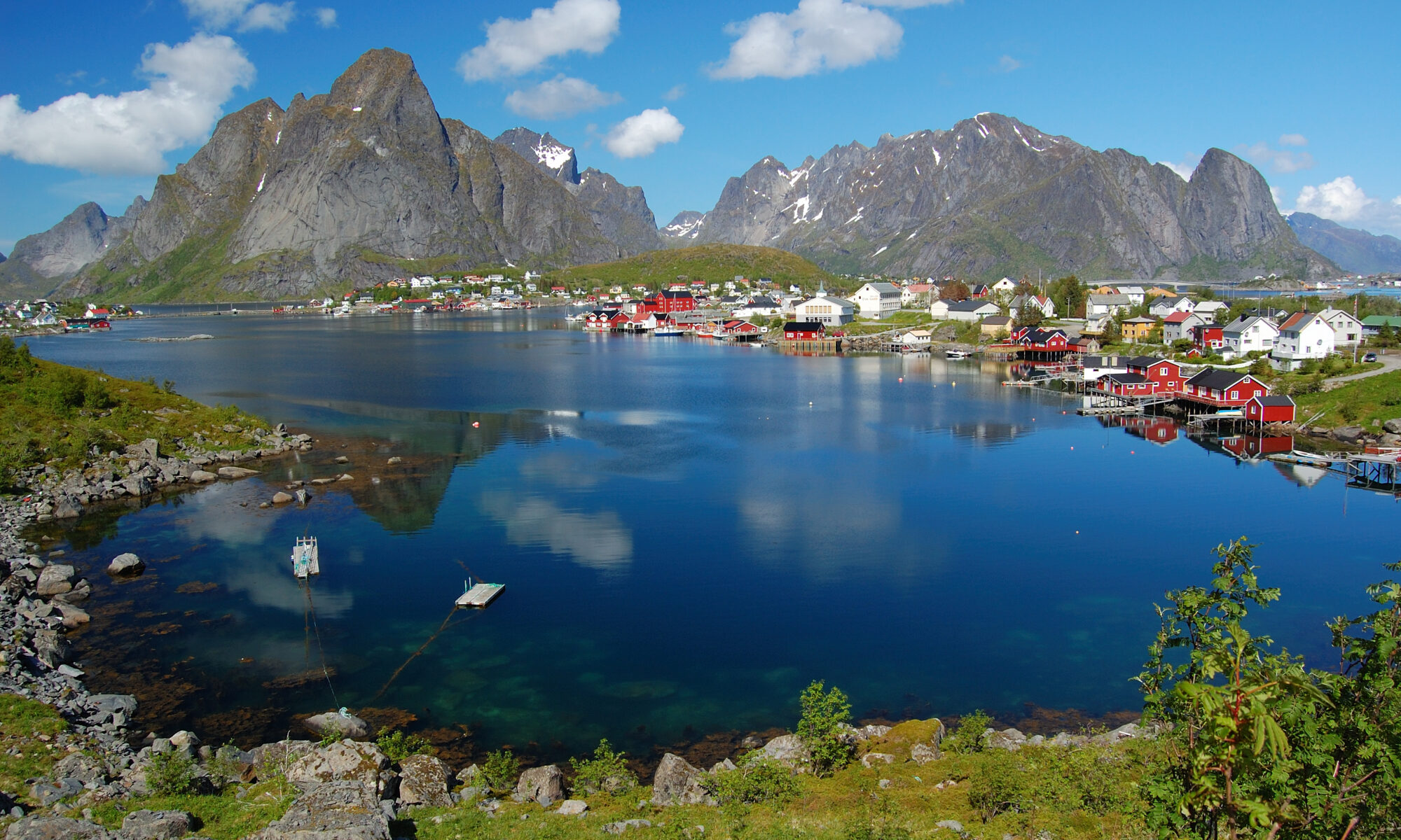 Red rorbuer cabins in Reine village beneath jagged peaks in the Lofoten Islands, Norway