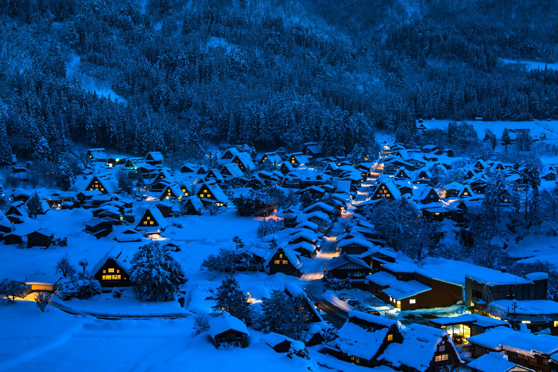 Snow covered gassho farmhouses lit up at night in Shirakawa-go, Japan in winter