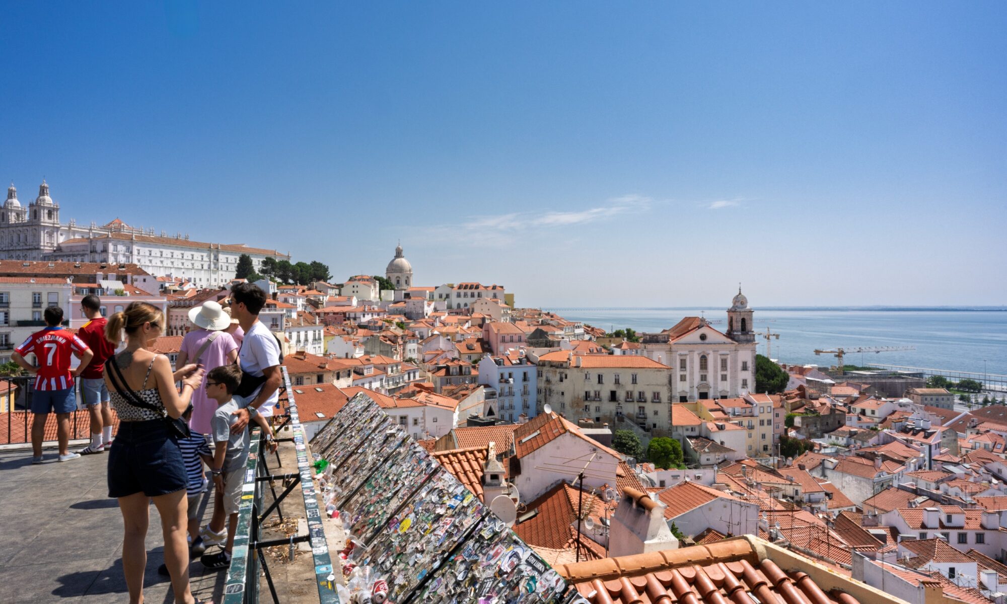 Terracotta rooftops of the Alfama district and the Tagus River seen from a Lisbon viewpoint