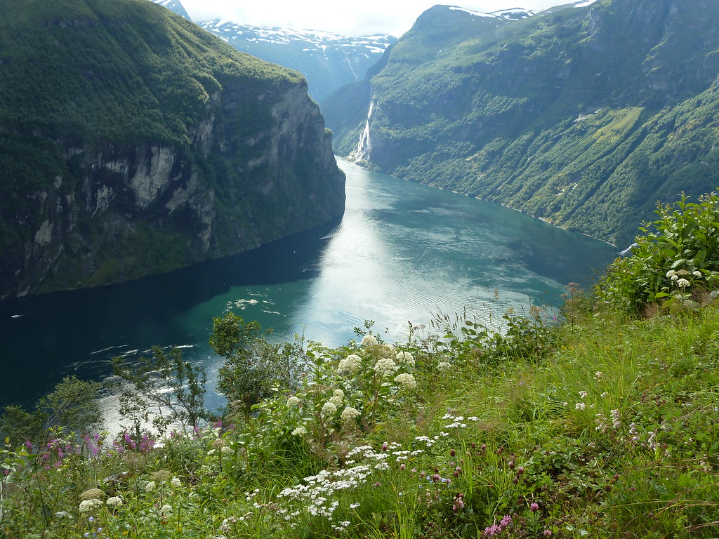 Steep green cliffs rising from the water of Geirangerfjord in Norway