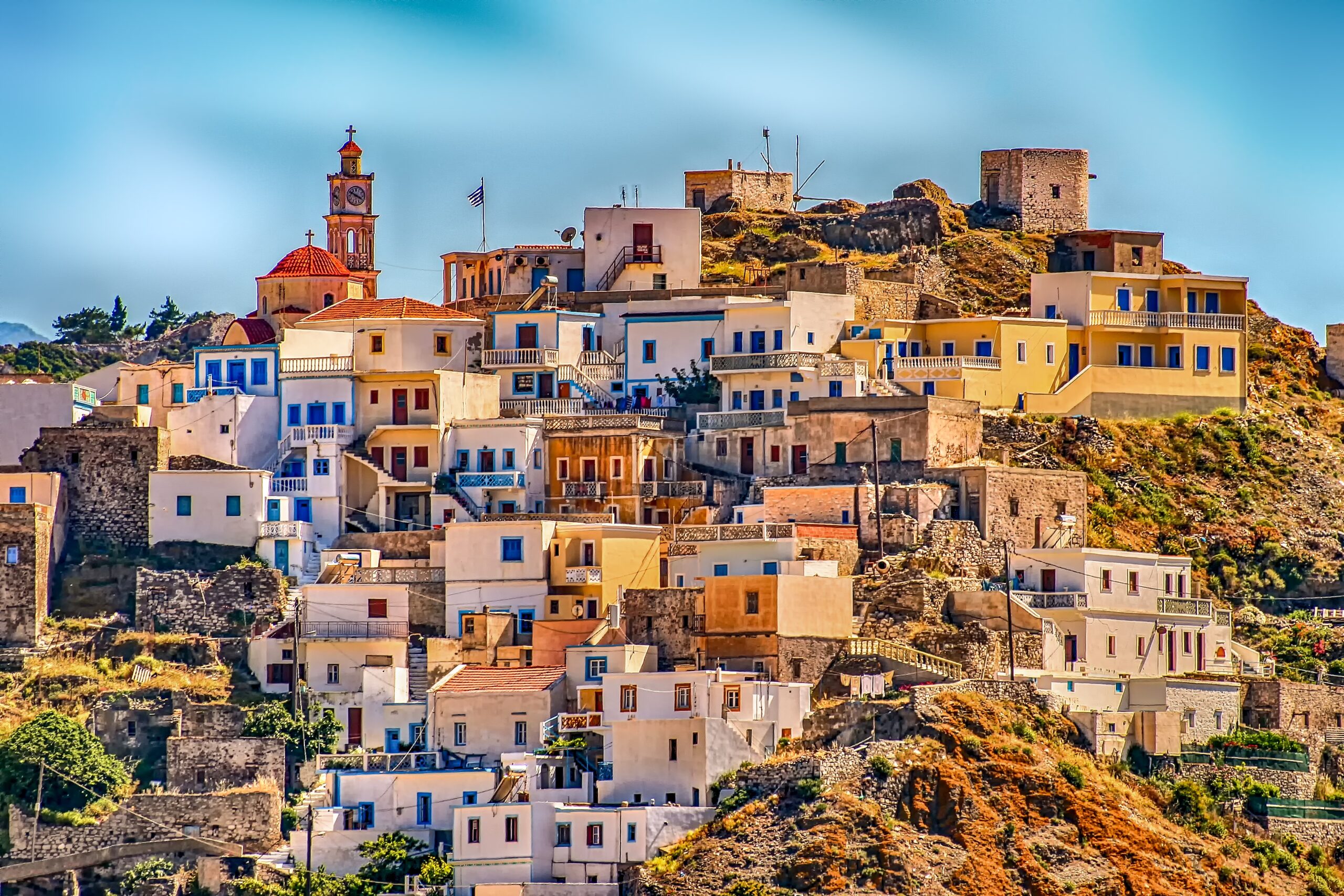 Colourful hillside village houses stacked above the sea on a Greek island