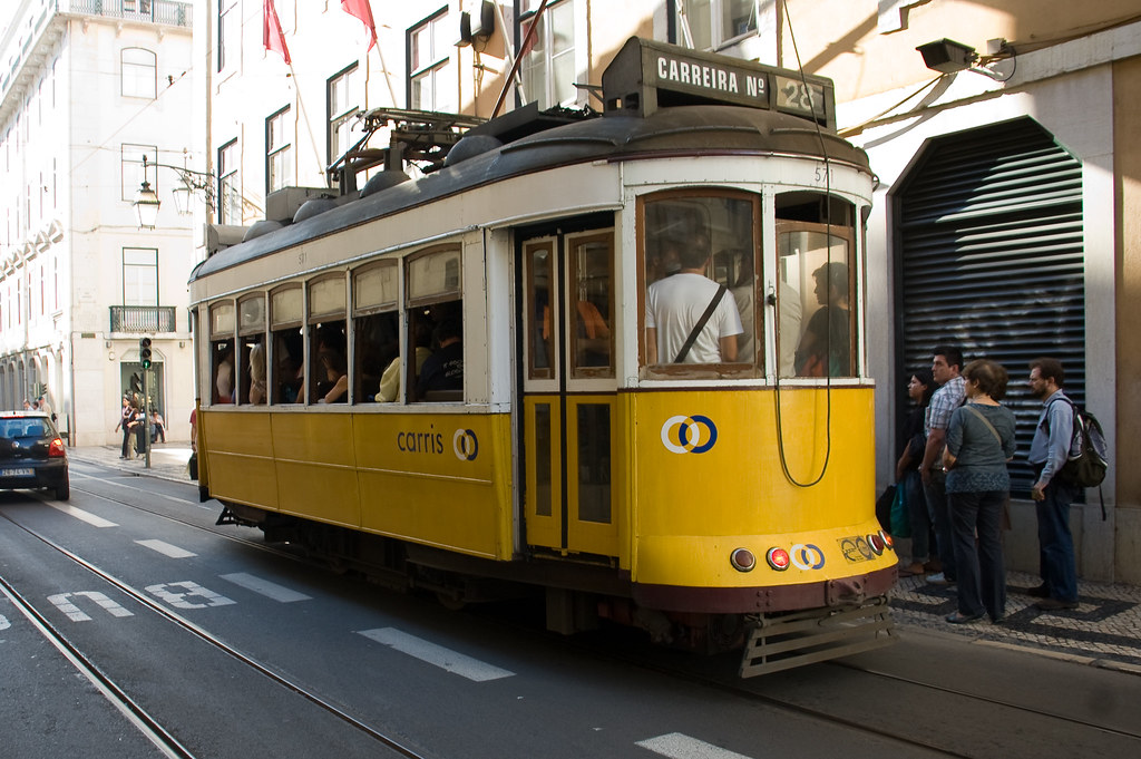 Historic yellow Tram 28 climbing a narrow street in Lisbon, Portugal