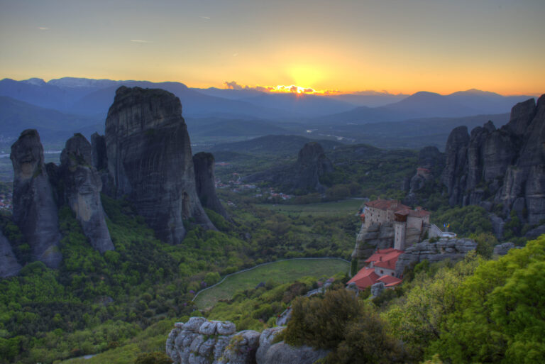 Sandstone pillars of Meteora glowing at sunset above the Thessalian plain