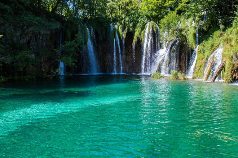 Cascading waterfalls pouring into a turquoise lake at Plitvice Lakes National Park