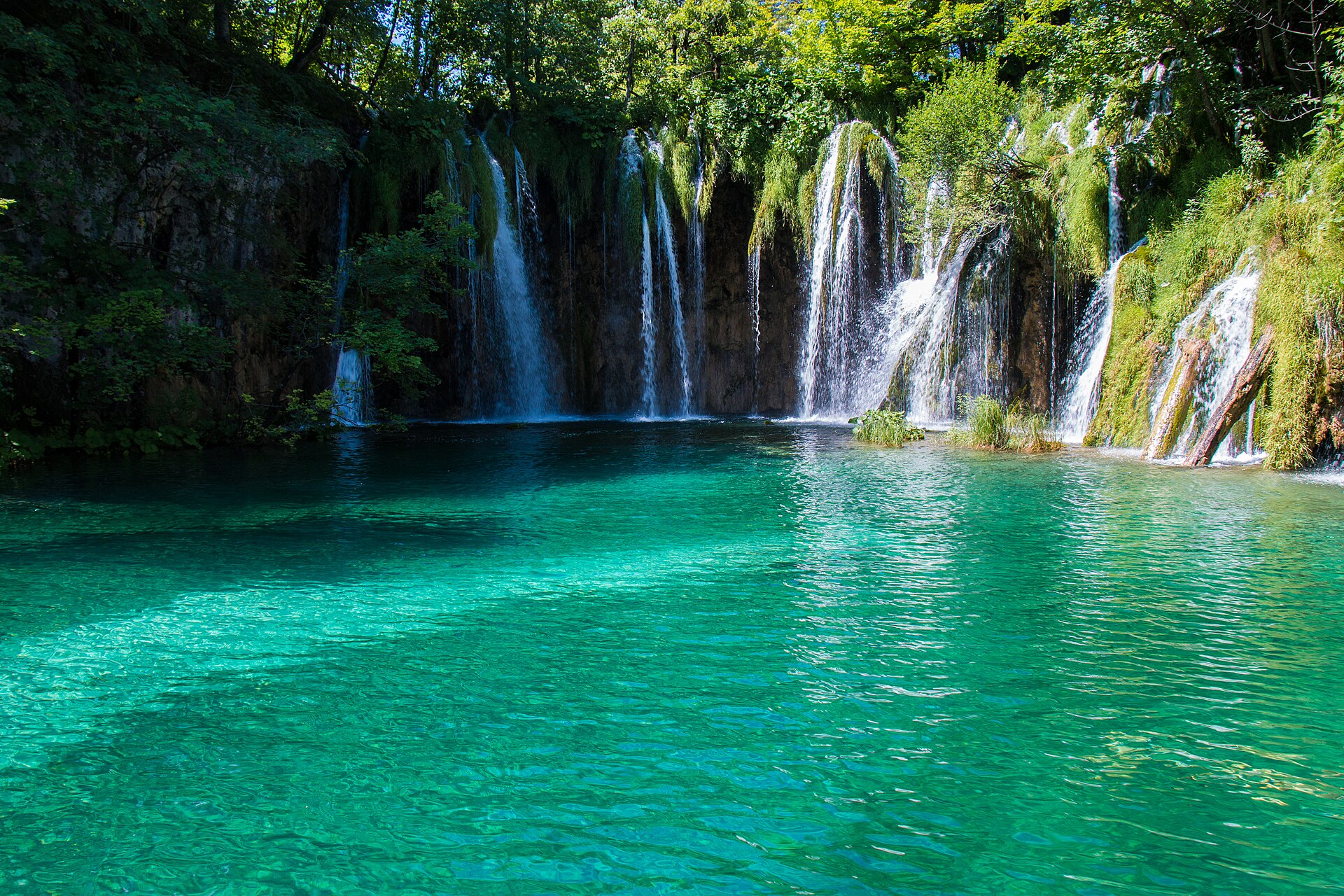 Cascading waterfalls pouring into a turquoise lake at Plitvice Lakes National Park
