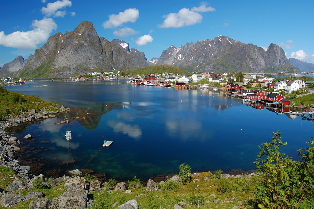 Red rorbu cabins beneath granite peaks in Reine Lofoten Islands