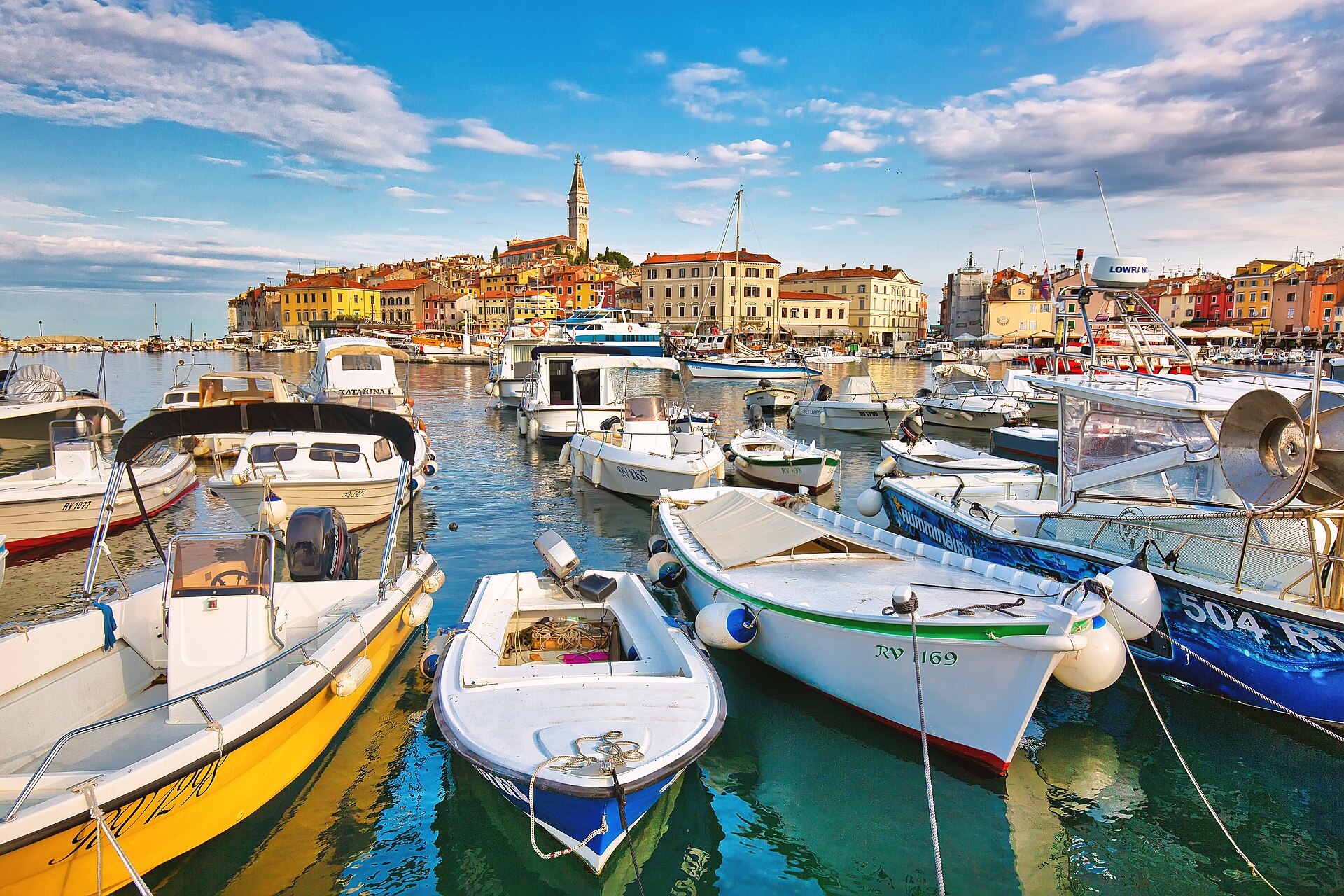 Fishing boats moored in Rovinj harbour with the colorful old town rising behind