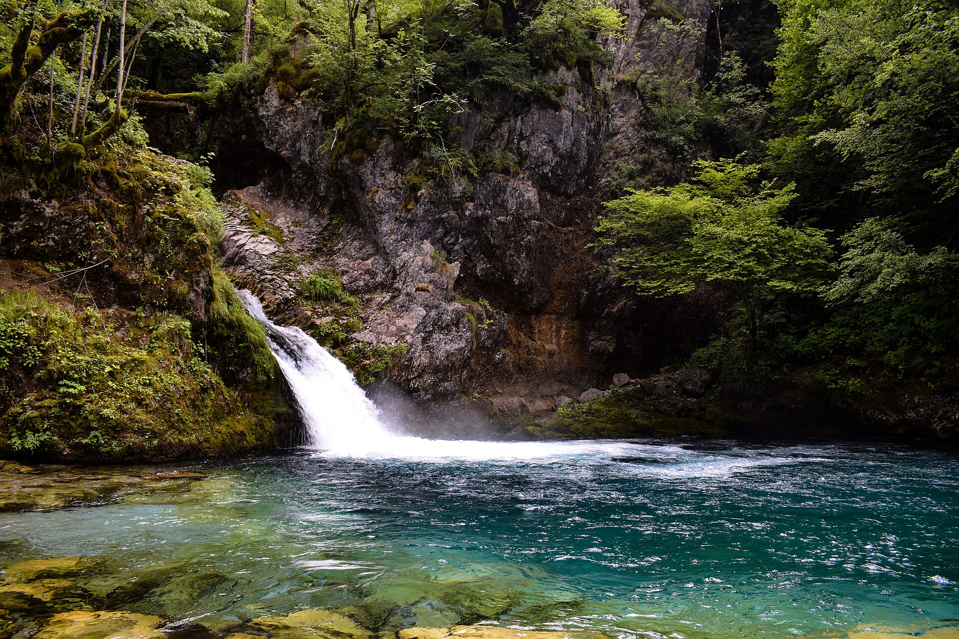 Turquoise glacial pool and waterfall at the Blue Eye of Theth in the Albanian Alps