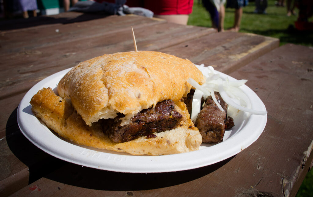 A plate of Bosnian cevapi with somun flatbread and raw onion, the cheapest good meal in the country