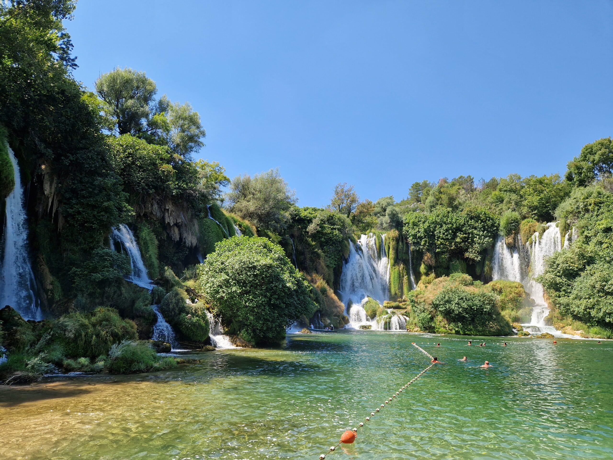 Kravice Waterfalls dropping in a wide crescent into a green swimming pool
