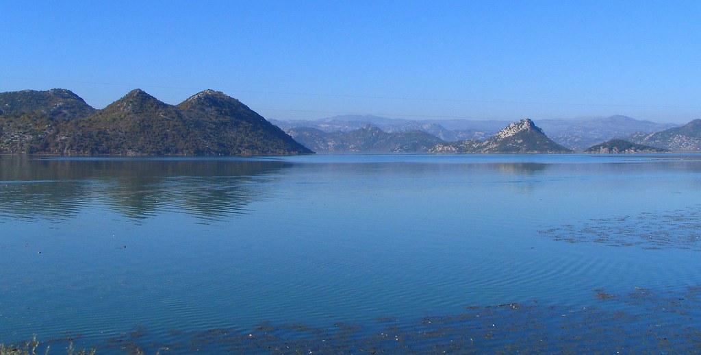Calm blue water of Lake Shkodra with mountains on the Albania and Montenegro border