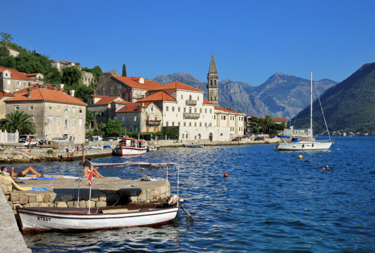 The stone waterfront and bell tower of Perast seen from the west across the Bay of Kotor
