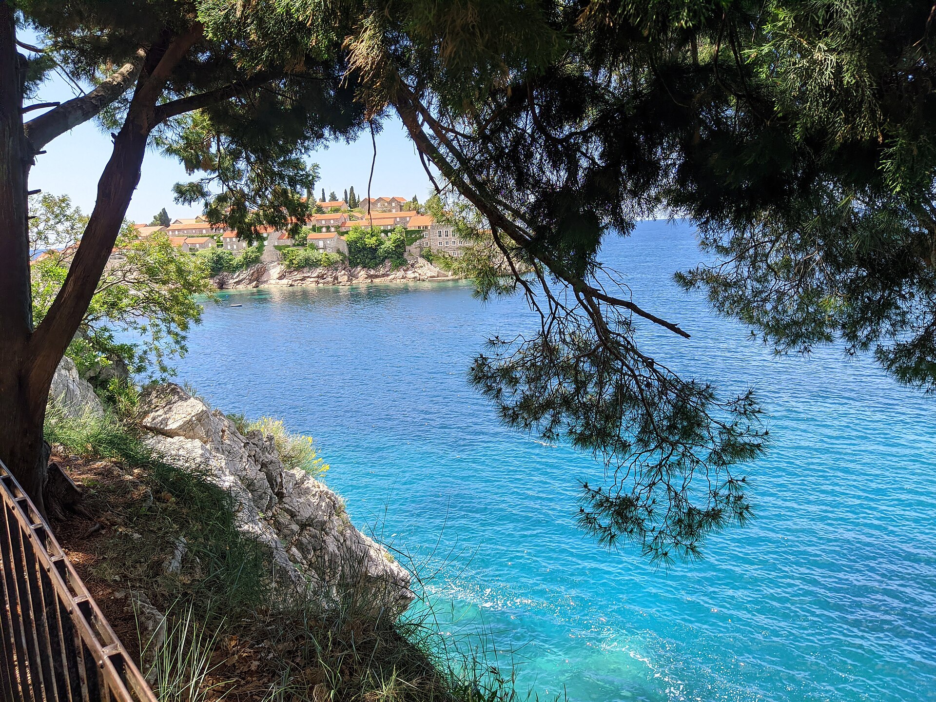 Pink pebble beach and clear turquoise water beside the Sveti Stefan causeway